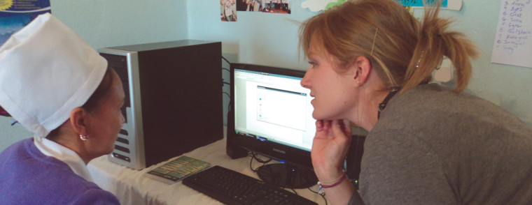 Kera Halverson, once a Peace Corps volunteer turned recruiter, helps a woman learn basic computer skills. Members of the Peace Corps volunteer and travel to foreign countries to live with and help people. 